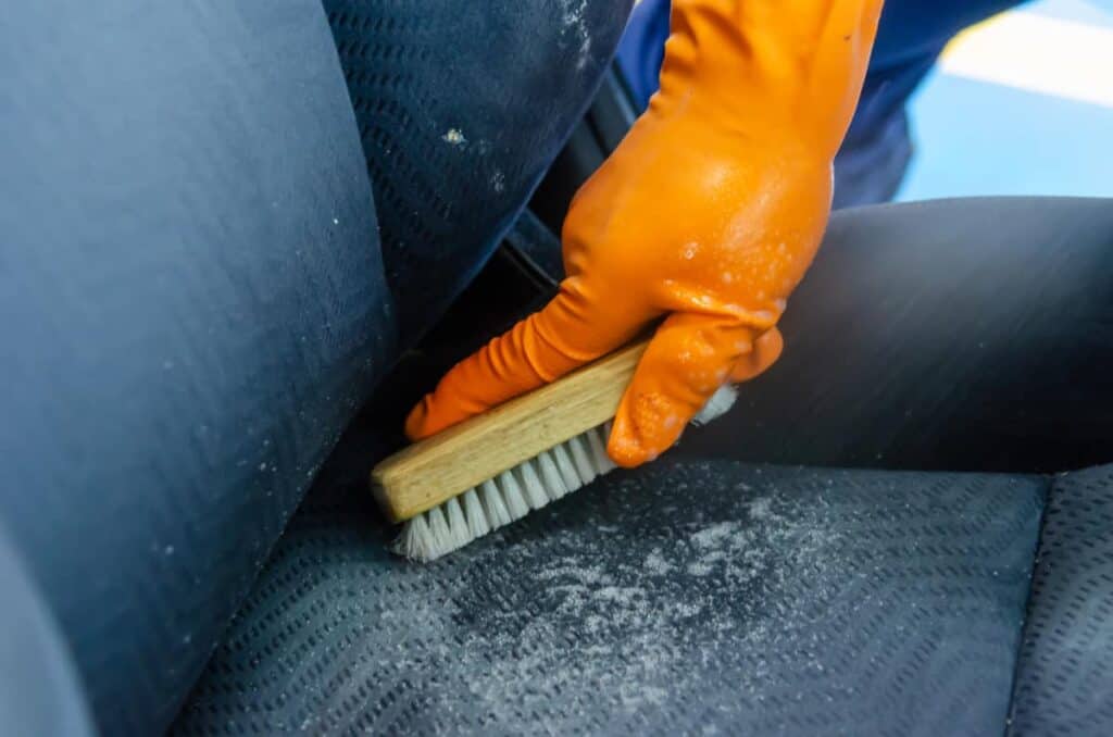 best way to clean vomit from a car, gloved hand with scrubbing brush